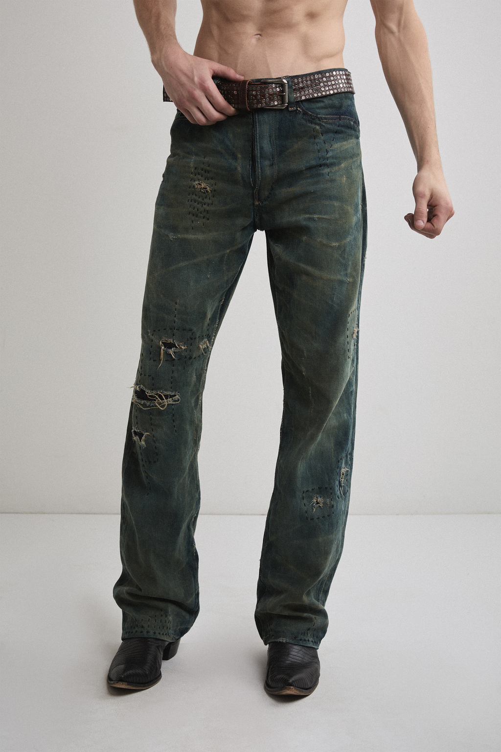 Close-up view of Tyler Andersen wearing brown AOA belt with rivets on denim.