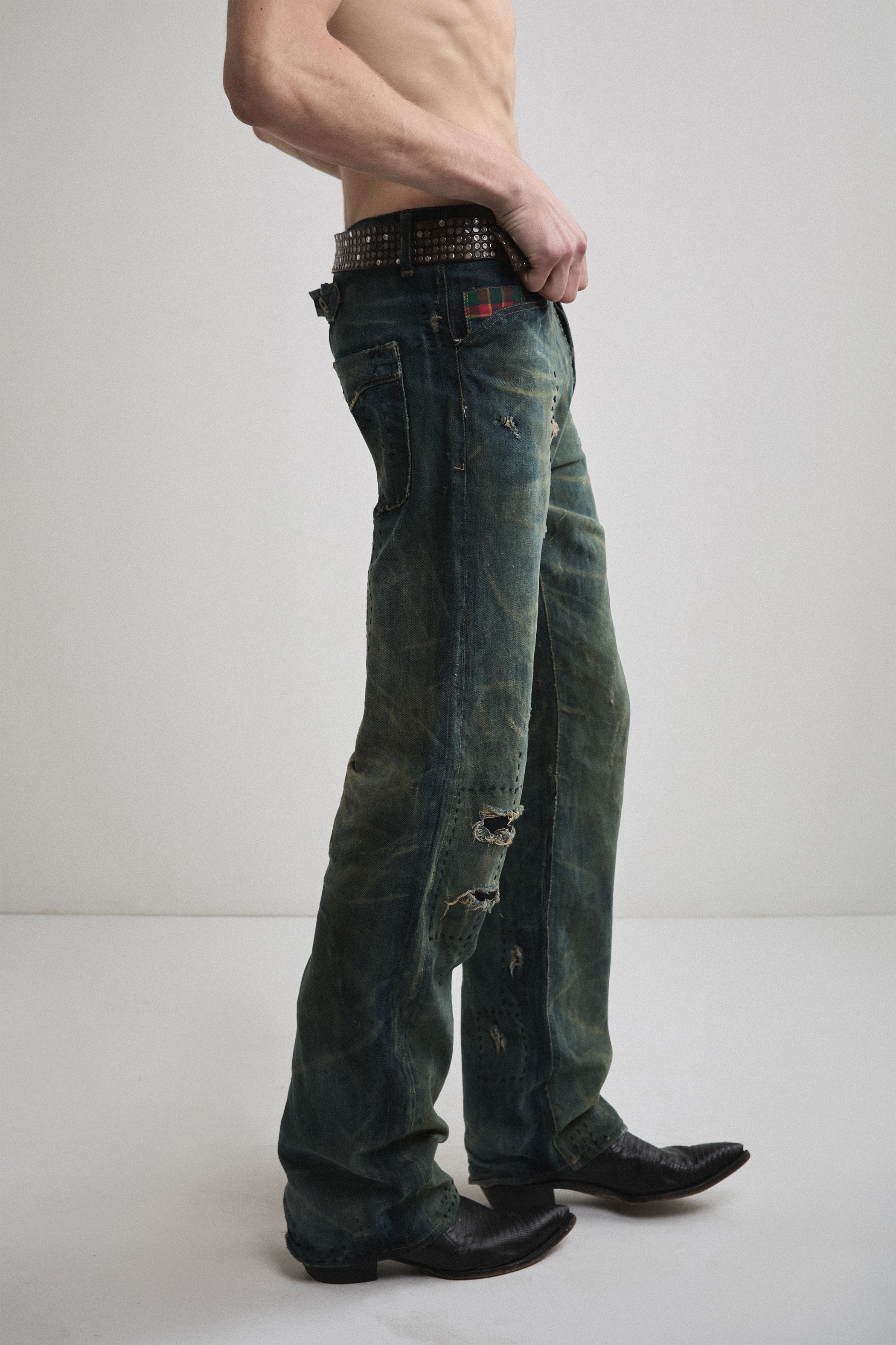Close-up right side view of Tyler Andersen wearing brown AOA belt with rivets on denim.