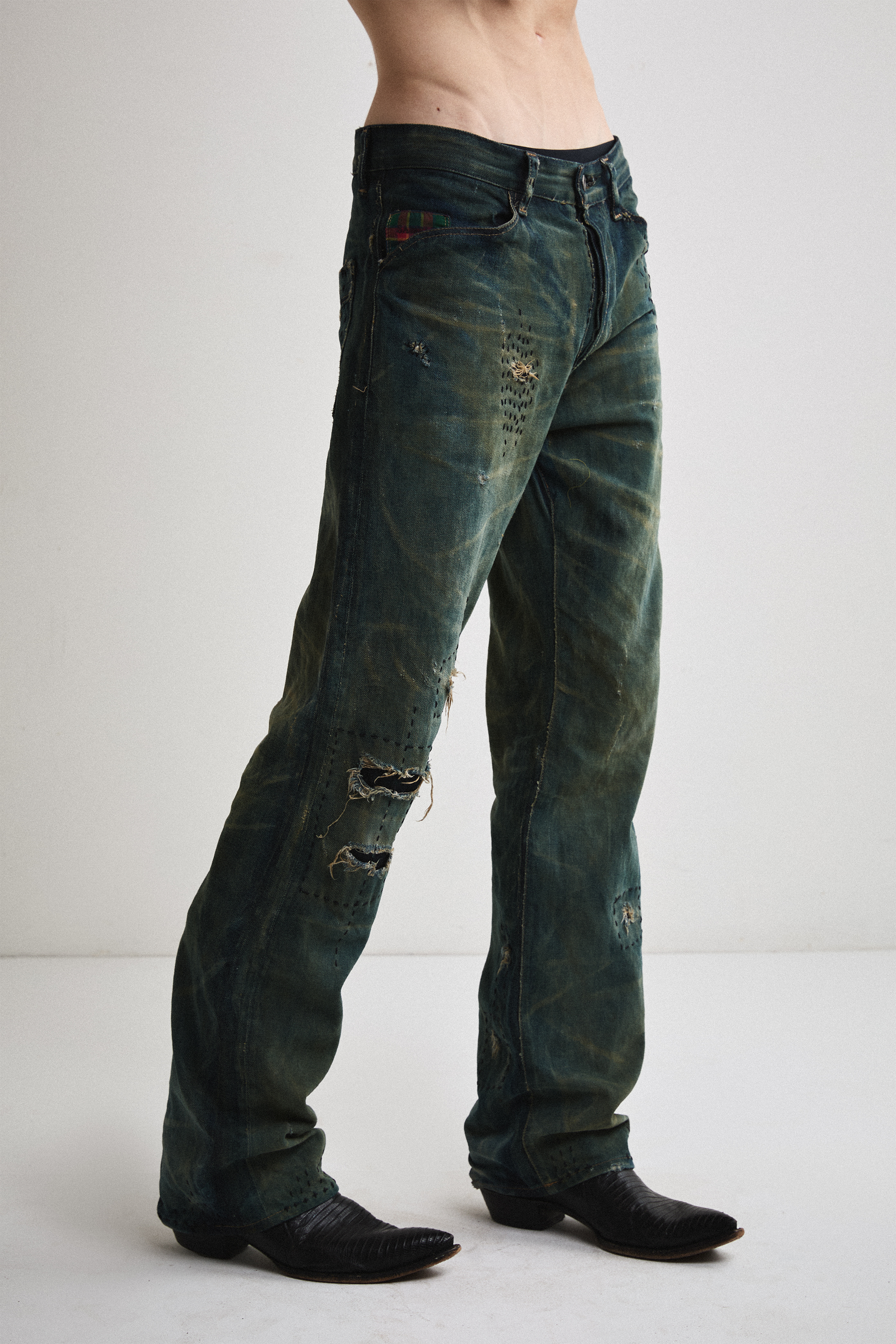 Close-up right side view of Tyler Andersen wearing distressed AOA Sashiko repaired denim