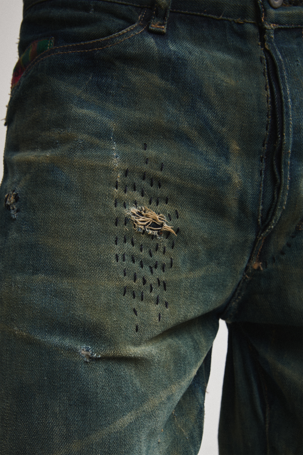 Ultra close-up front view of distressed AOA Sashiko repaired denim showing upper stitching details
