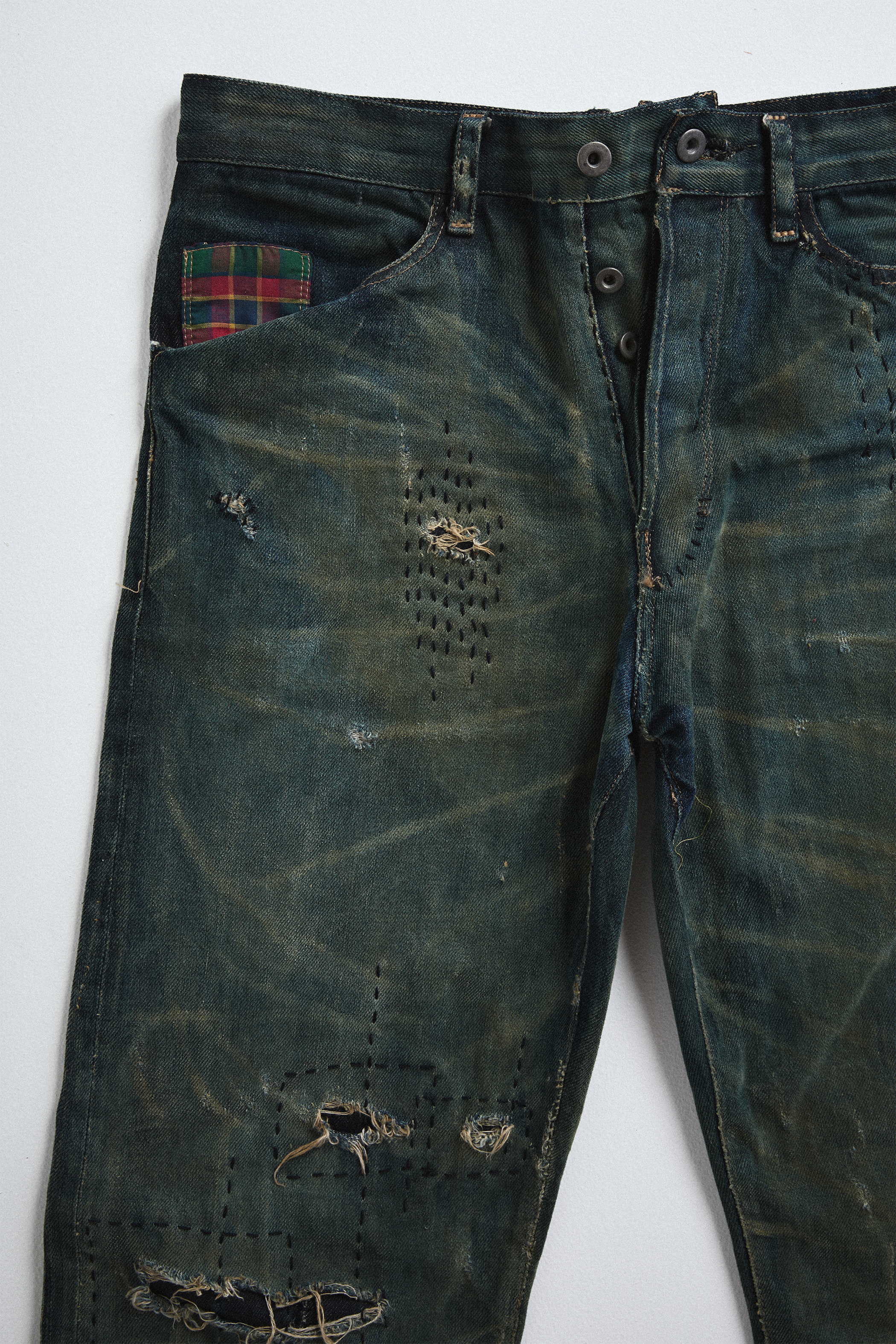 Ultra close up front view of distressed AOA Sashiko repaired denim showing stitching detail