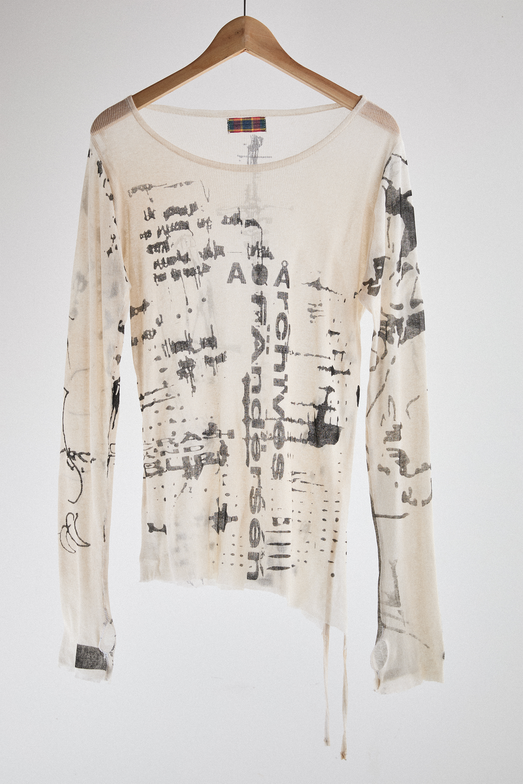 Front view of sheer long-sleeve AOA cream top with black text and graphics designed to look like tattoos.