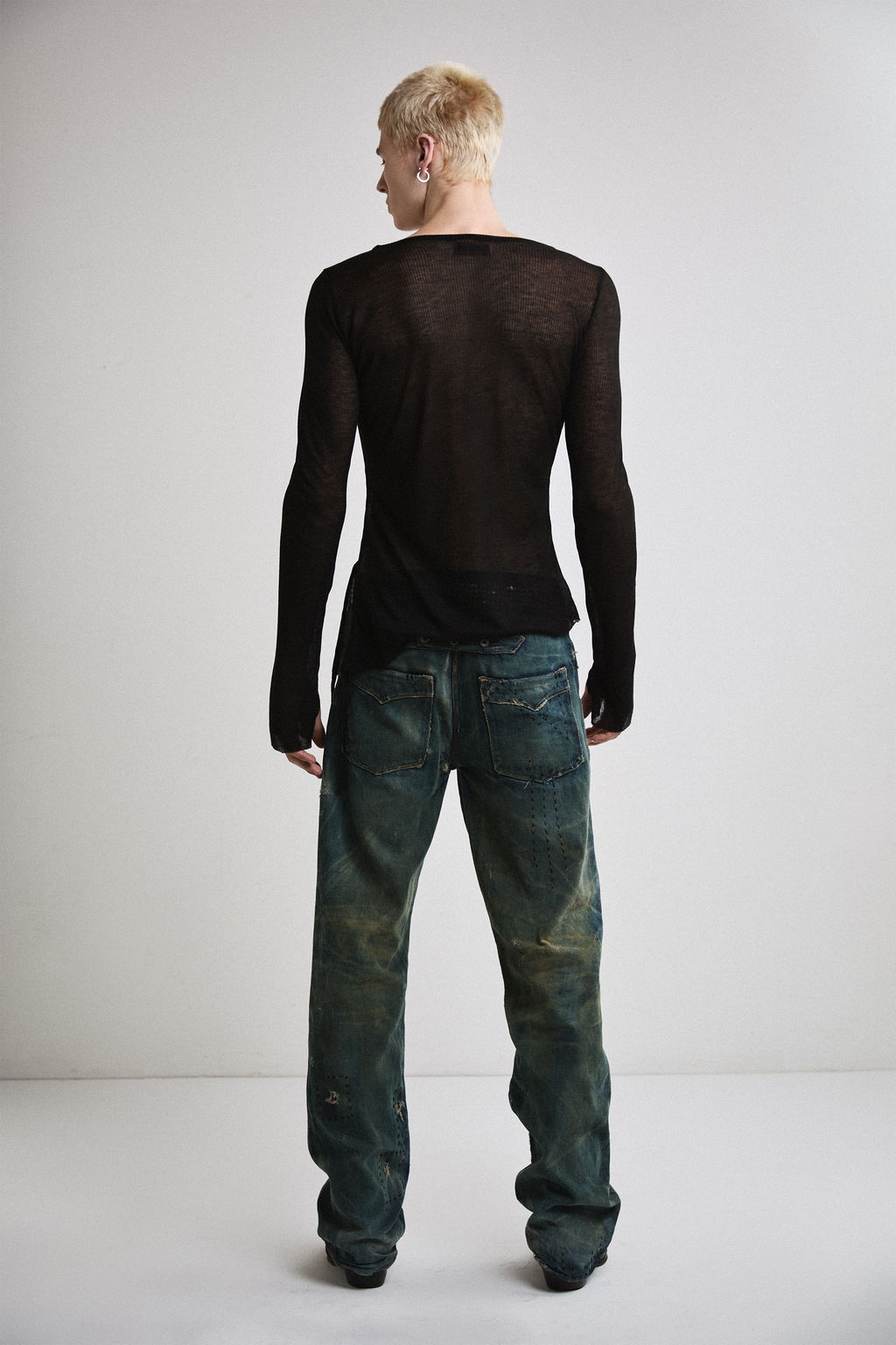 Back view of Tyler Andersen wearing sheer long-sleeve AOA Black top.