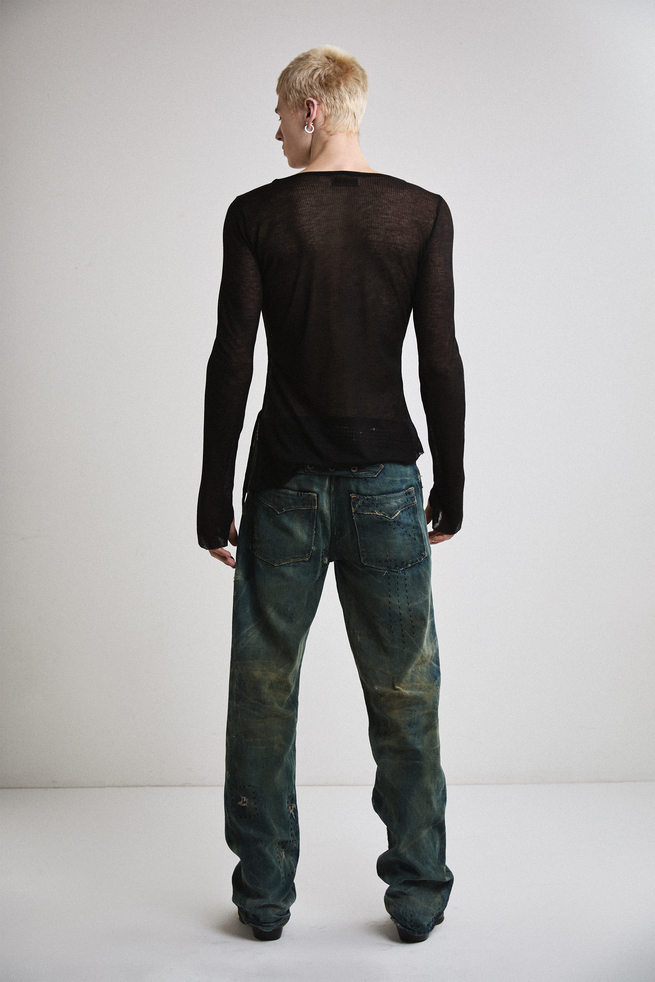 Back view of Tyler Andersen wearing sheer long-sleeve AOA Black top.