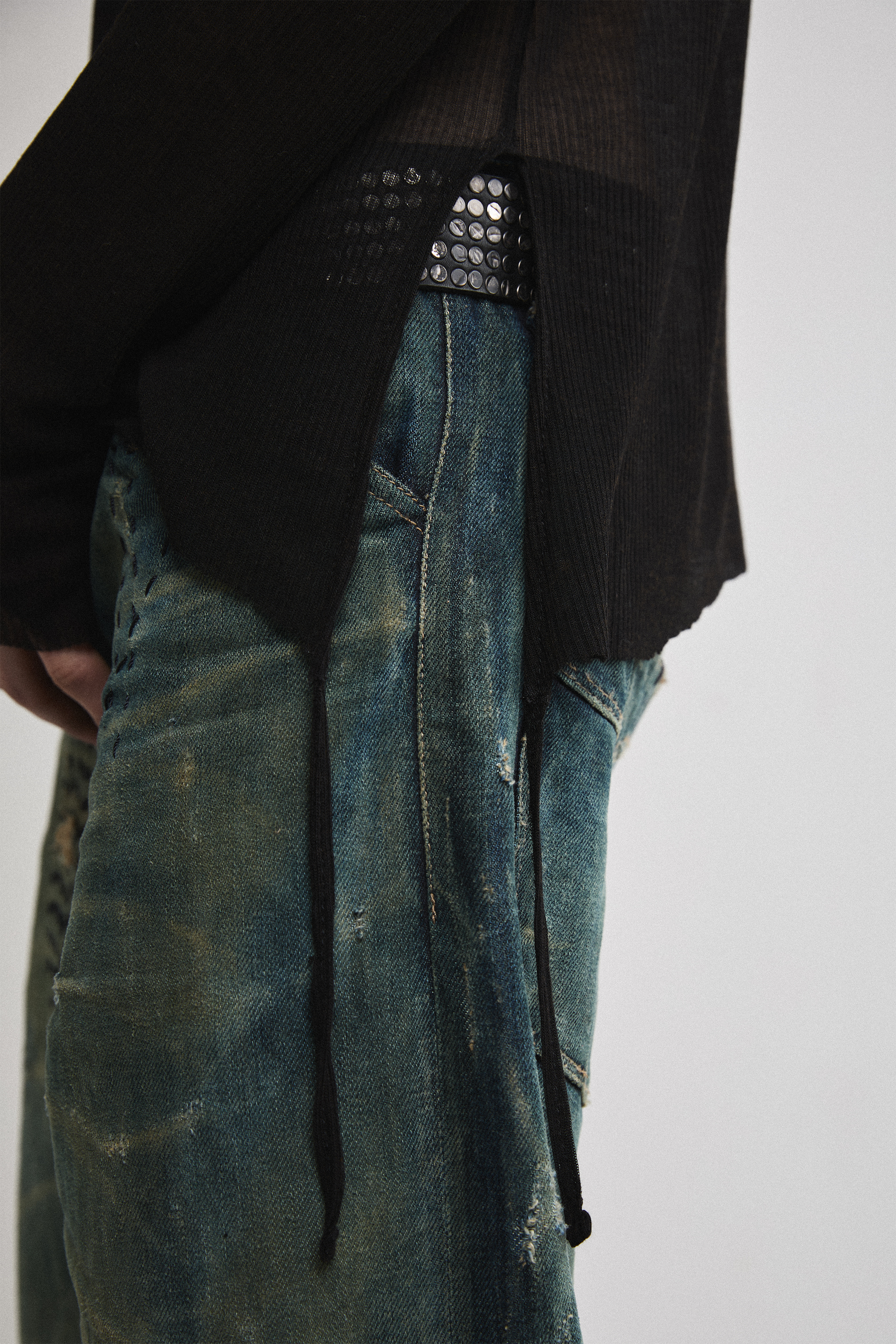 Left close-up side view of Tyler Andersen wearing sheer long-sleeve AOA Black top showing tassels.