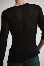 Close-up back view of Tyler Andersen wearing sheer long-sleeve AOA Black top.