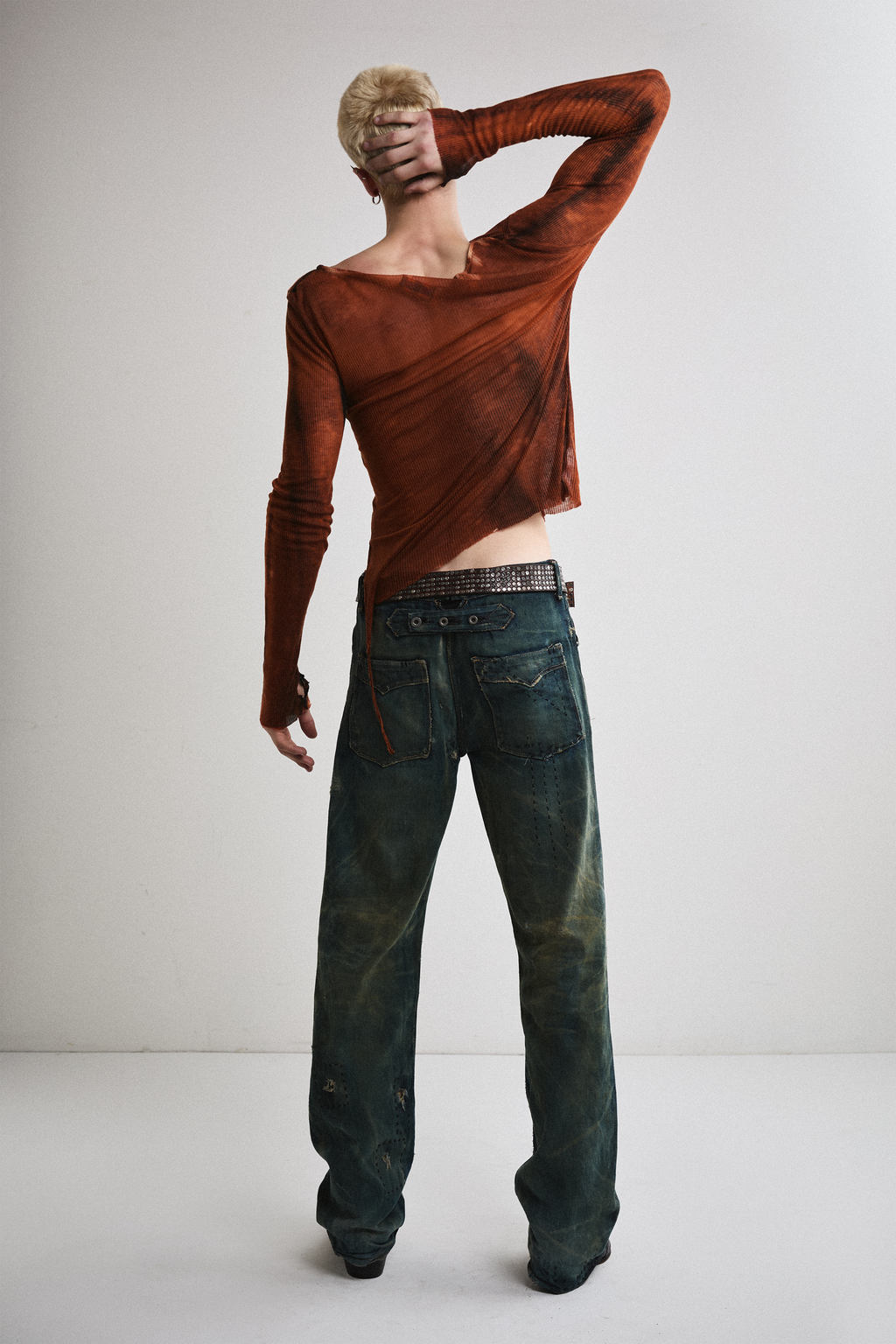 Back view of Tyler Andersen with hand on head wearing sheer long-sleeve AOA rust top.
