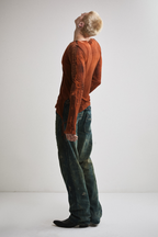 Left side view of Tyler Andersen wearing sheer long-sleeve AOA rust top.