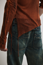Back view of Tyler Andersen wearing sheer long-sleeve AOA rust top showing tassels.