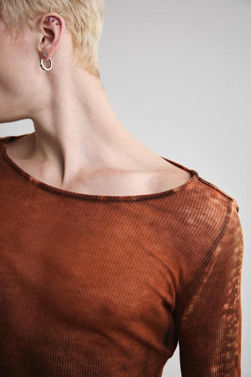 Ultra close-up view of Tyler Andersen looking left side view of Tyler Andersen wearing sheer long-sleeve AOA rust top.