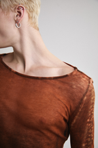 Ultra close-up view of Tyler Andersen looking left side view of Tyler Andersen wearing sheer long-sleeve AOA rust top.