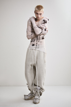 Front view of Tyler Andersen wearing a sheer long-sleeve cream AOA top with black text and graphics designed to look like tattoos.