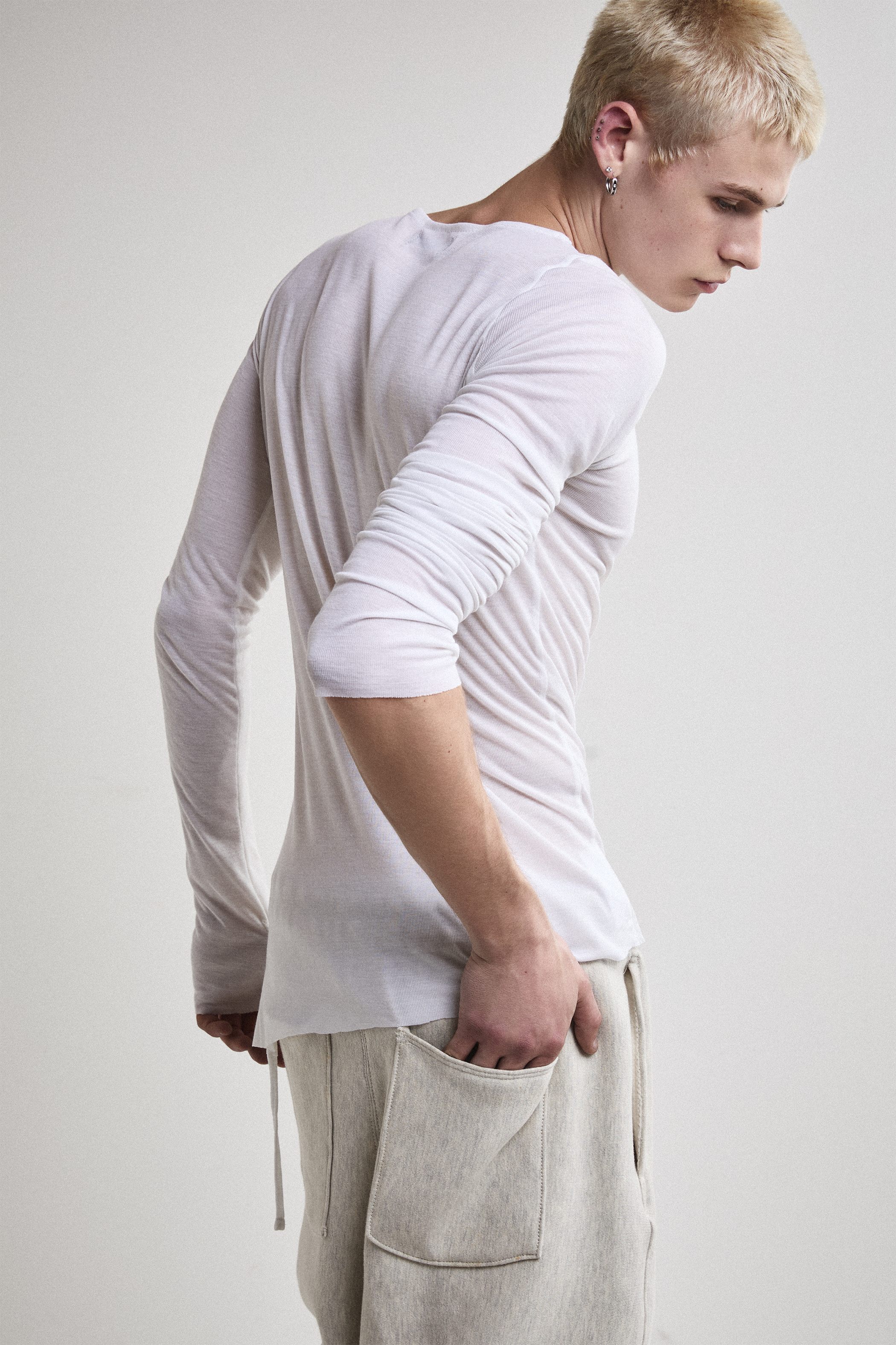 Close-up right side view of Tyler Andersen wearing sheer long-sleeve AOA White  top.