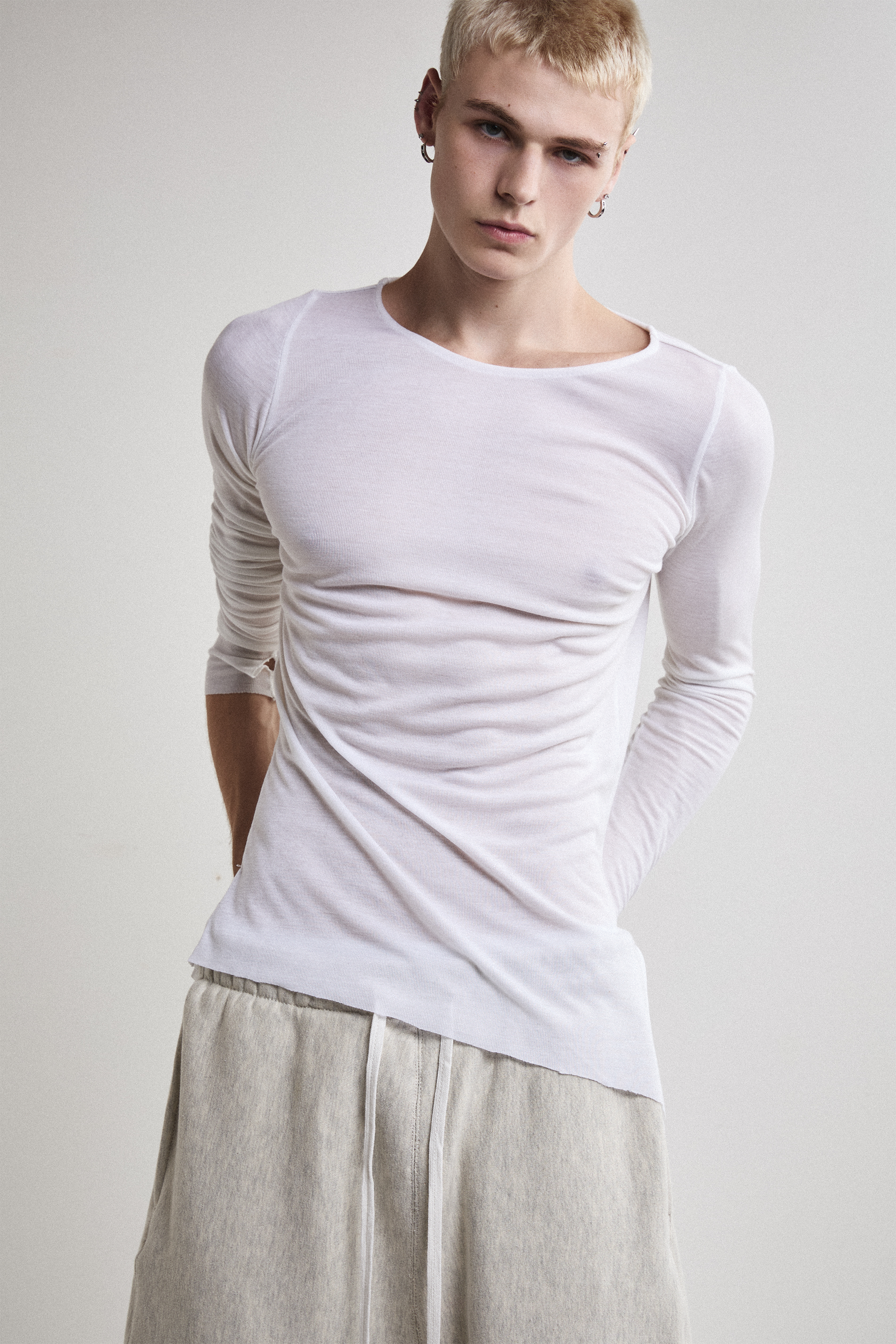 Close-up front view of Tyler Andersen wearing sheer long-sleeve AOA White  top.