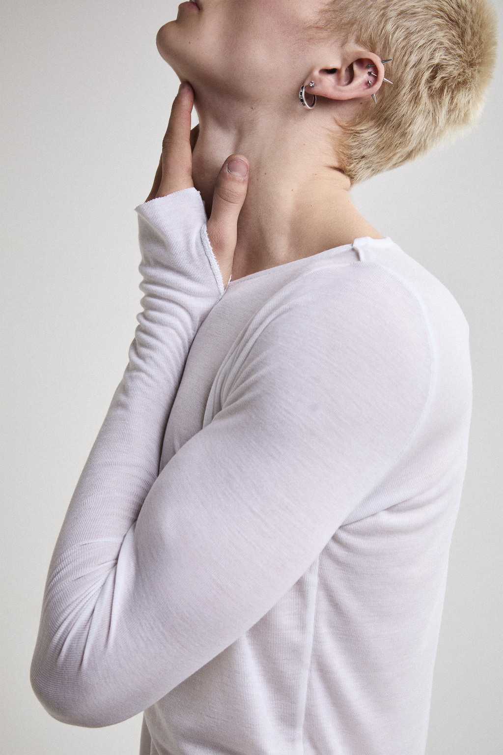 Close-up left side view of Tyler Andersen wearing sheer long-sleeve AOA White  top.