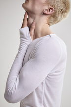 Close-up left side view of Tyler Andersen wearing sheer long-sleeve AOA White  top.